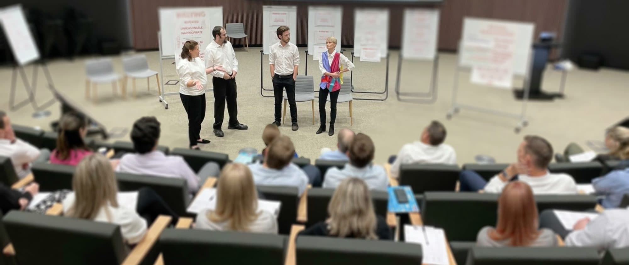 A team of Corporate Actors standing behind a corporate audience